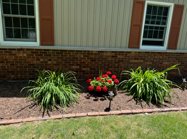 Mulch bed with flowers and plants along house foundation by BDS Lawns